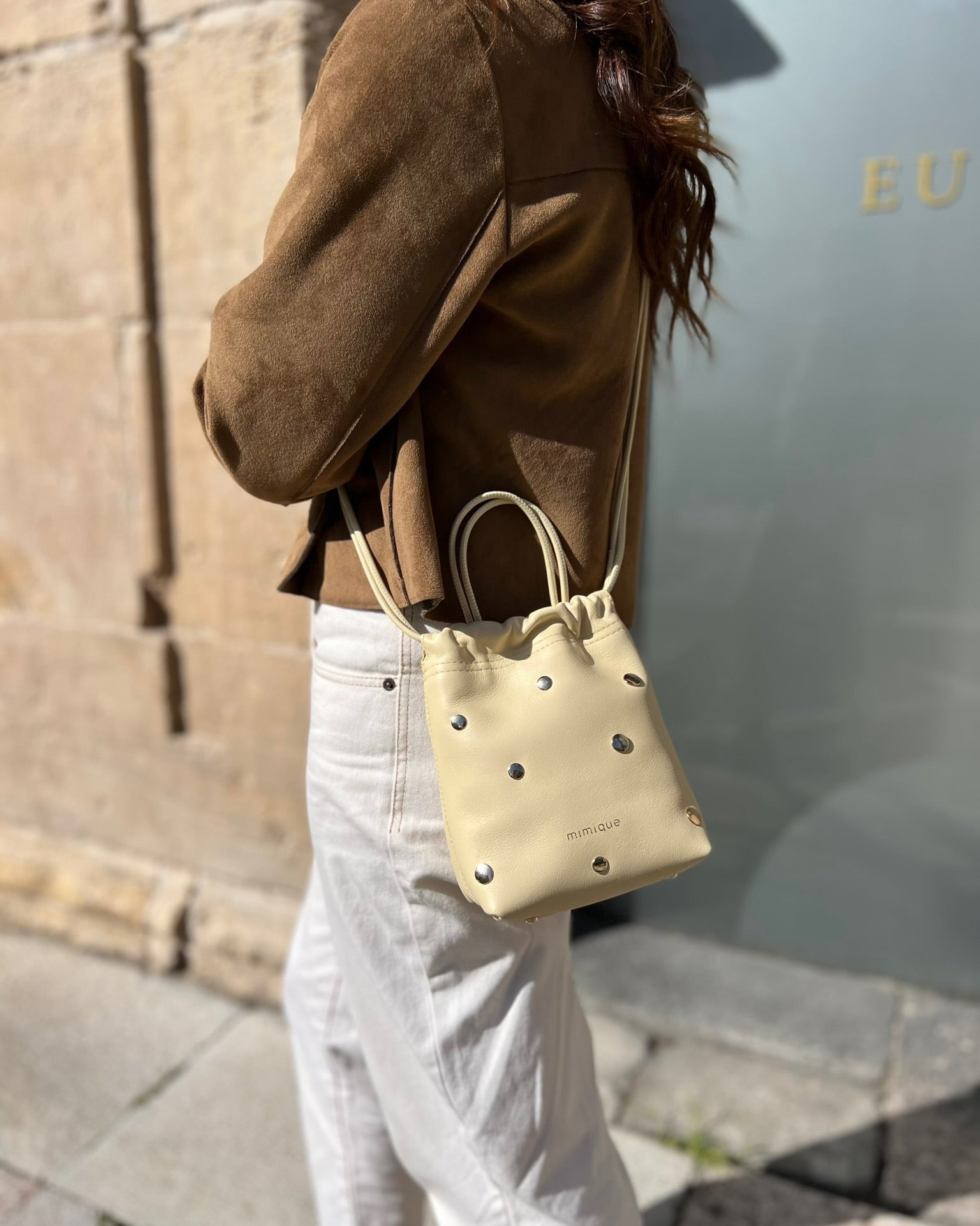 Bolso pequeño de piel para mujer Cue dots color mantequilla con tachuelas metálicas con acabado de oro viejo. Diseño de bombonera. Piel de máxima calidad. Hecho a mano en España