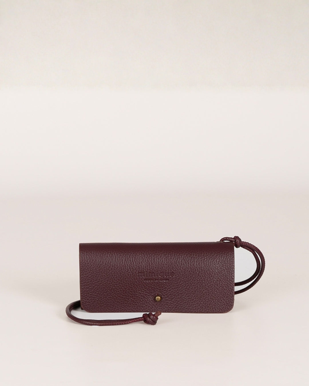 Funda de gafas de piel color burdeos de Mimique. Hecha a mano en España en piel de la mejor calidad con un diseño único y original. Lleva un cordón de piel poder colgarla. Entran todas las gafas.