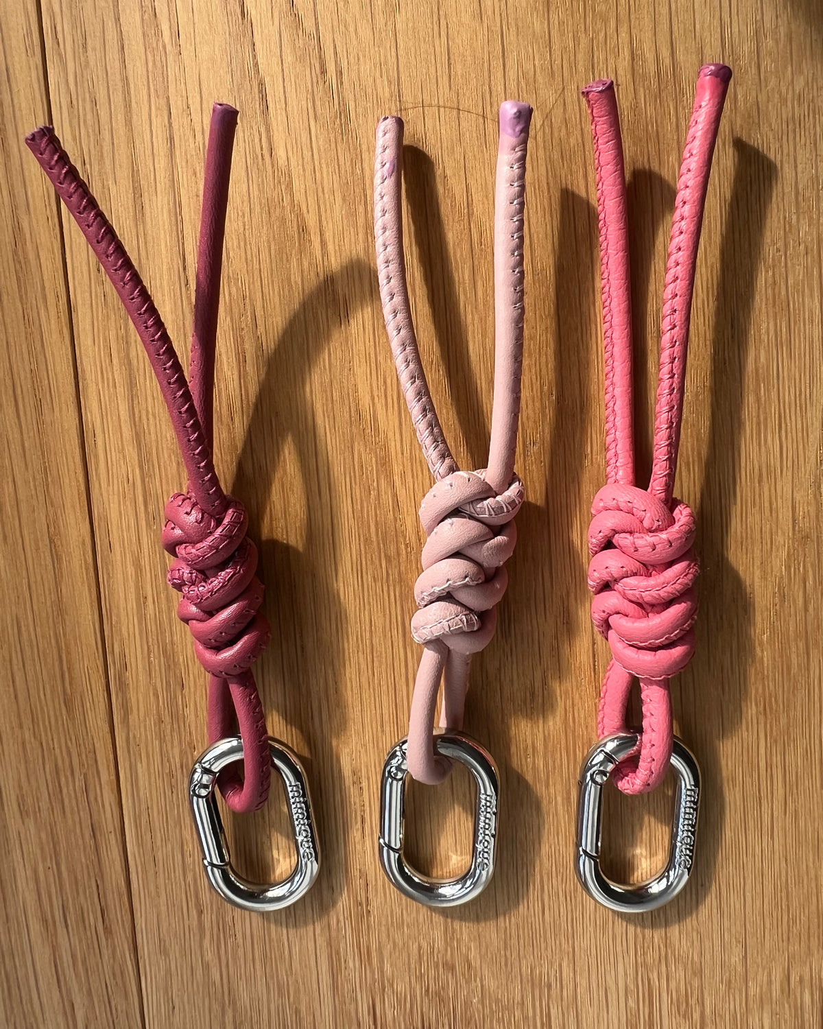 Llavero solidario de piel rosa Mimique con nudo de espiga y diseño de lazo lucha contra el cáncer de mama 
